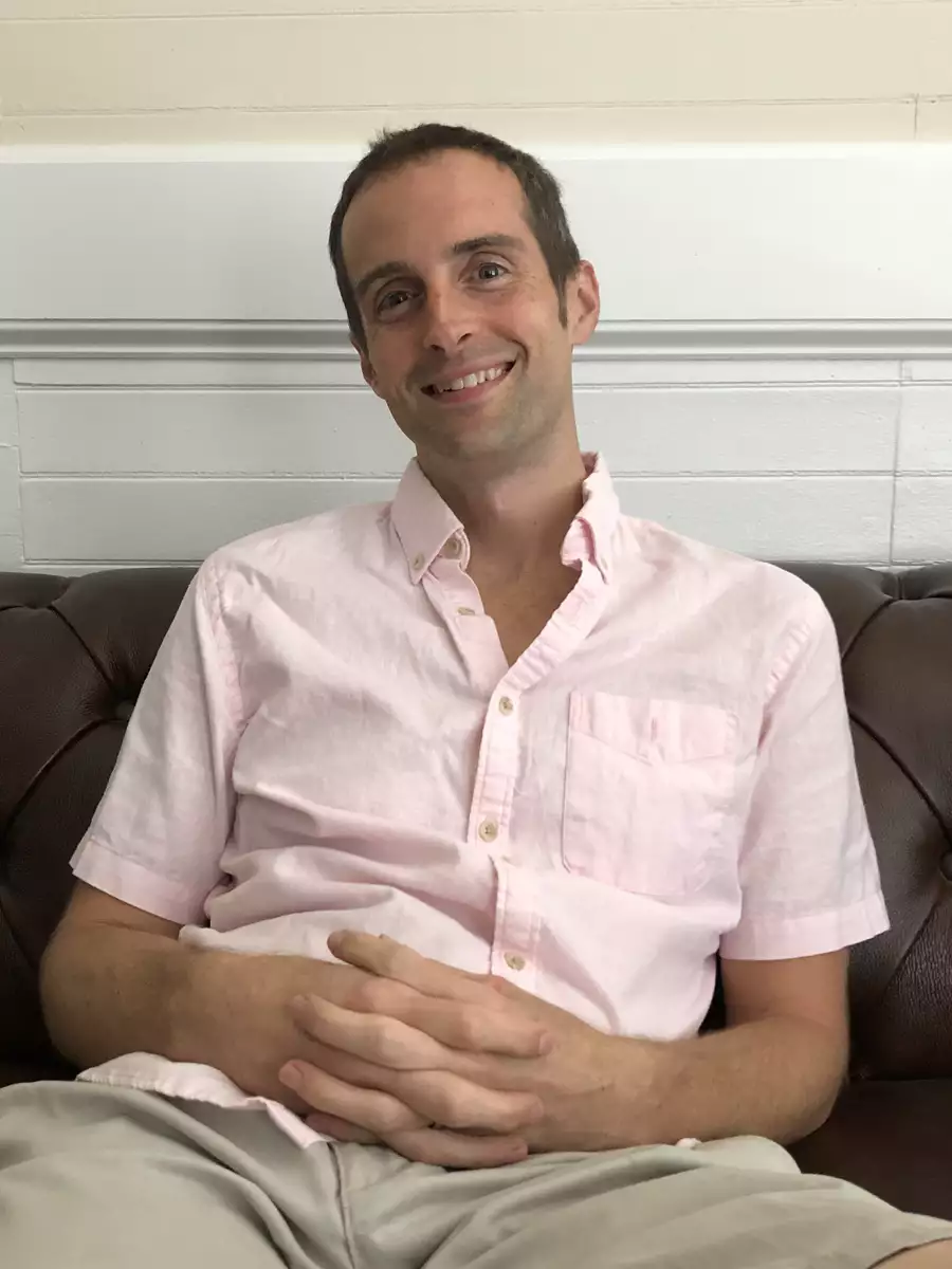 Jerry in a pink button-up shirt, relaxed and smiling