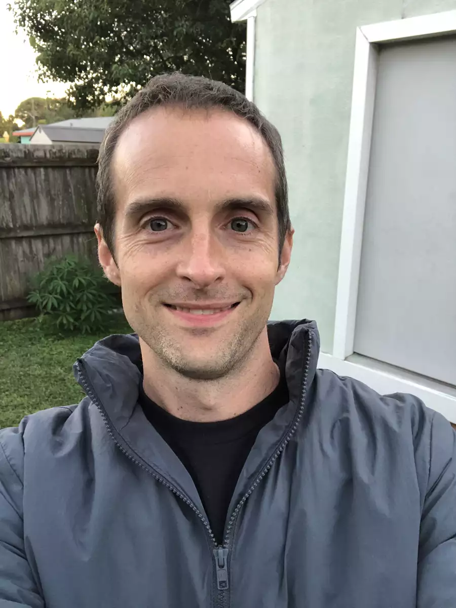 Jerry smiling outside in a gray jacket